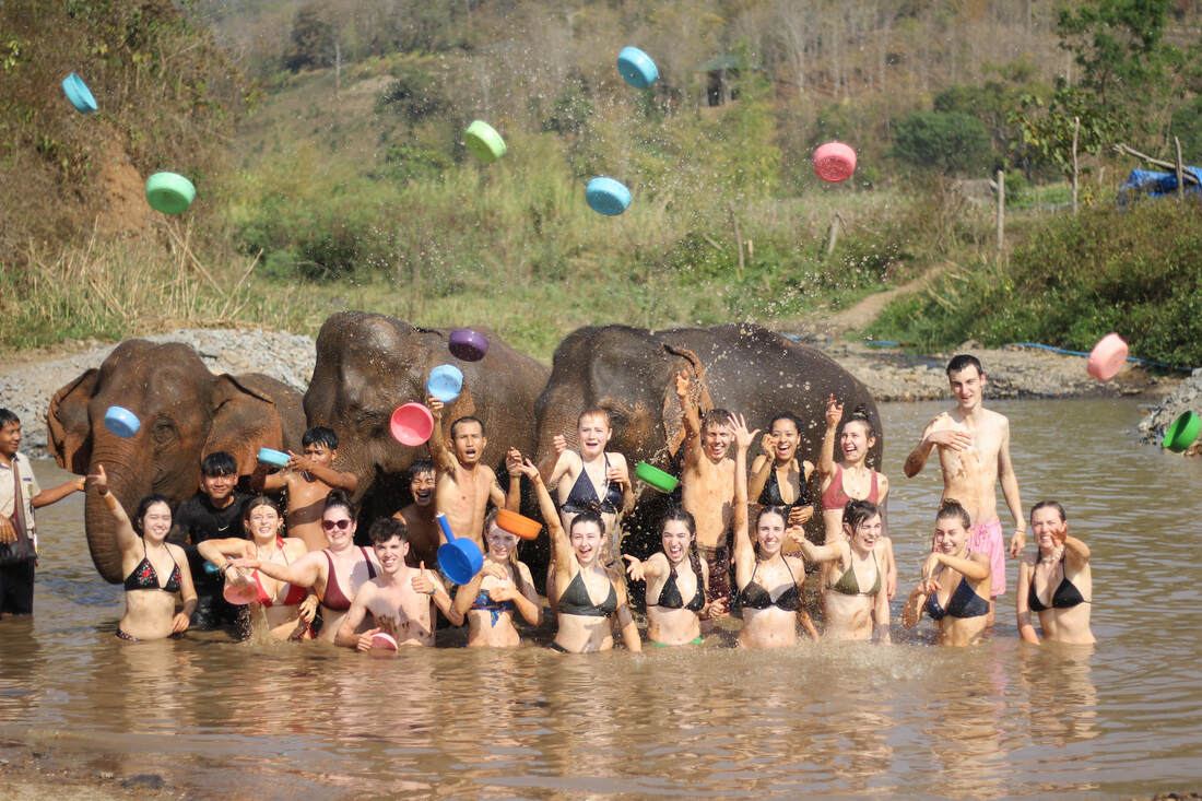 A group of visitors with the elephants in the river